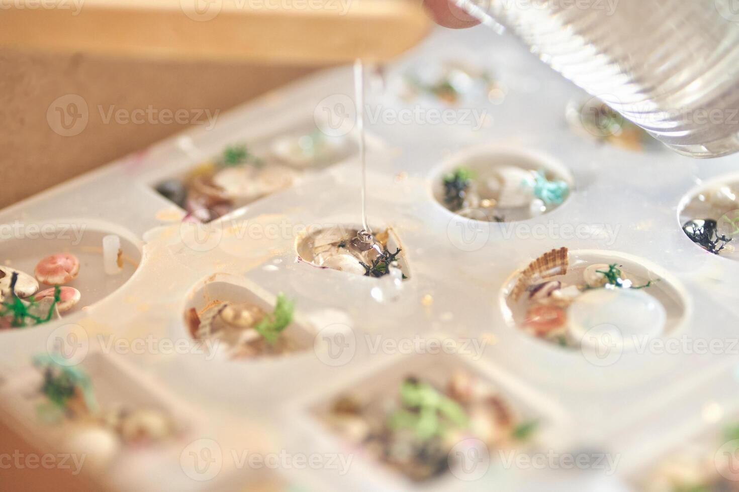 Handcrafted epoxy resin jewelry mold with shells and flowers in artistic process. photo