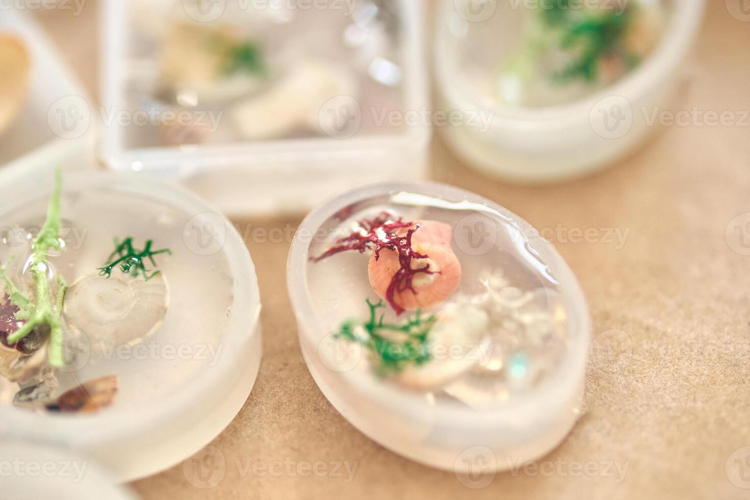 Handmade resin decorations with seashells and coral embedded in oval molds for unique coastal themed art and craft projects. photo