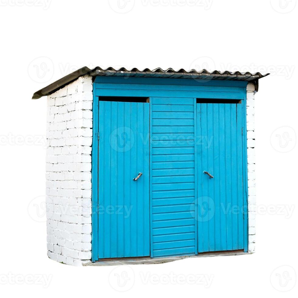 Bright blue wooden double doors on small white brick shed with corrugated metal roof. photo