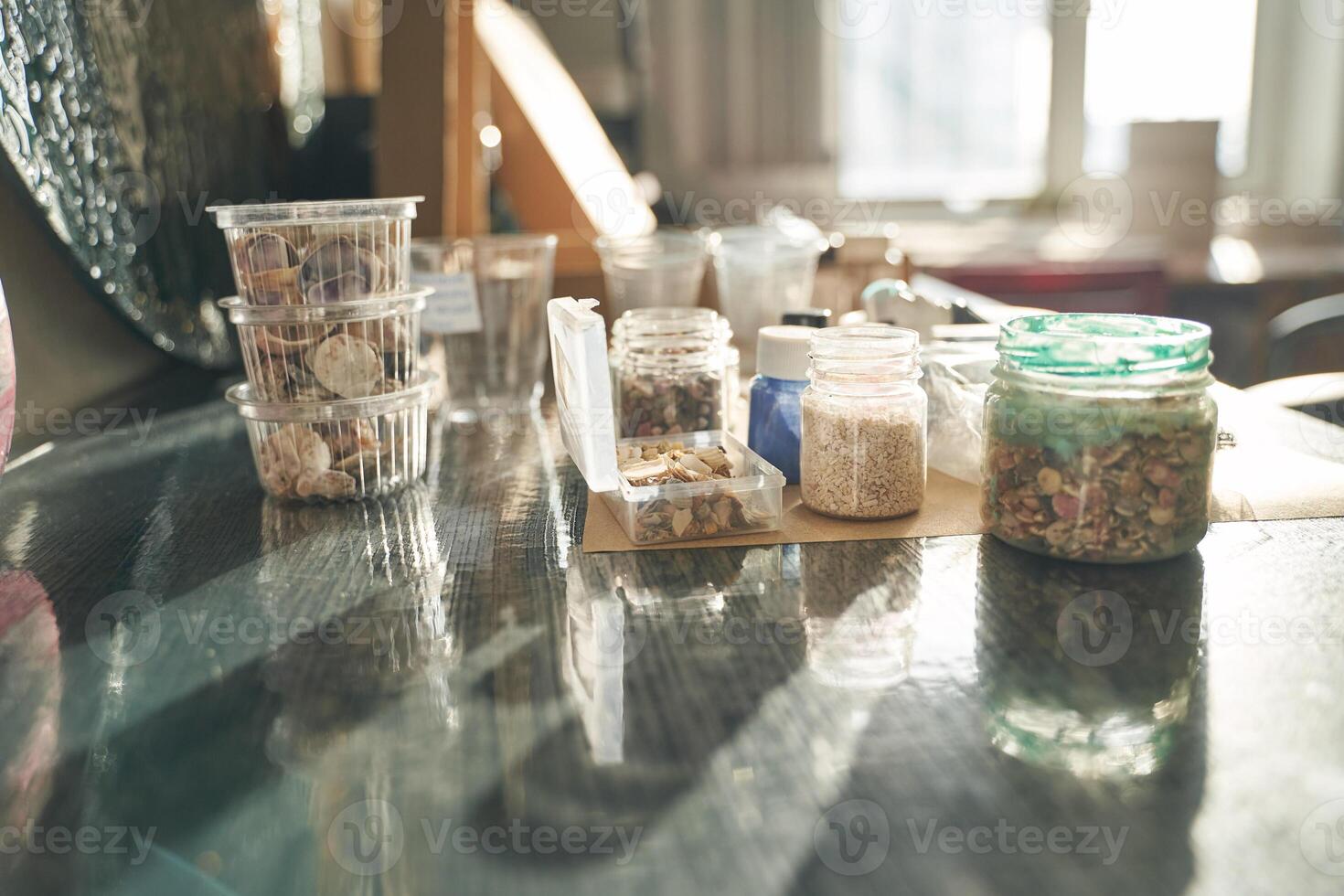 Sunlit crafting space with various jars and containers on a wooden table near a window. photo