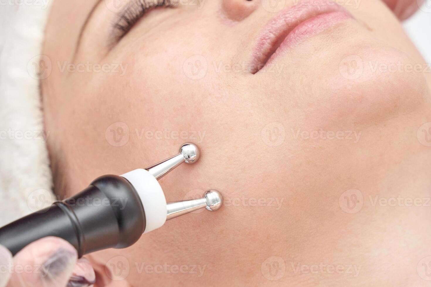 Young caucasian female receiving non invasive microcurrent facial treatment for skin rejuvenation. photo