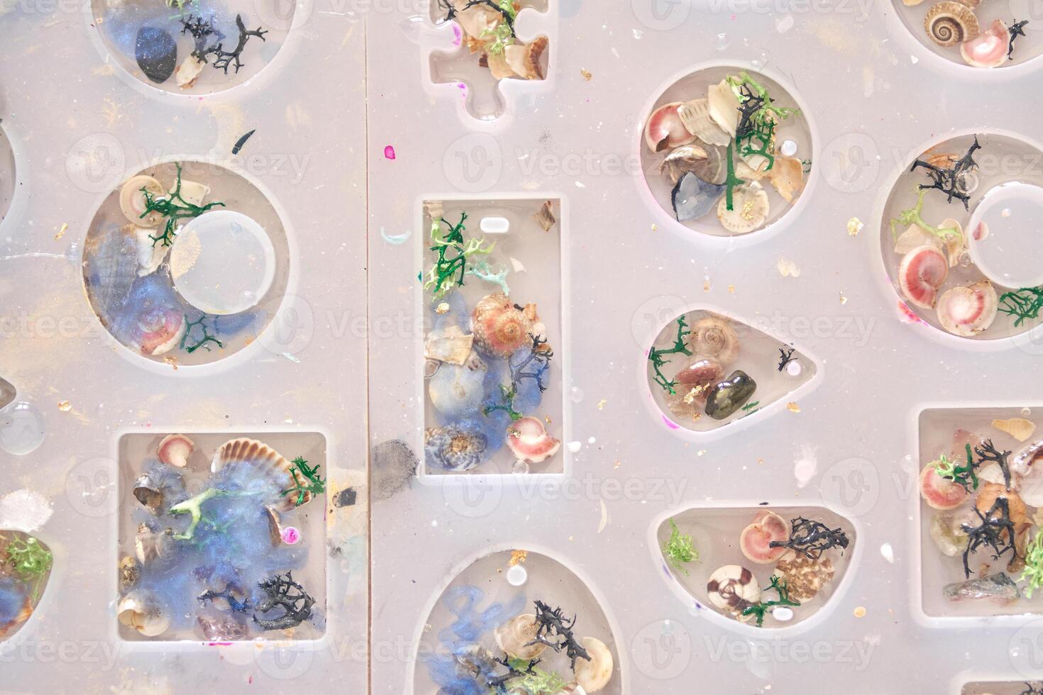 Creative resin art with colorful shells and decorative elements in mold shapes. photo