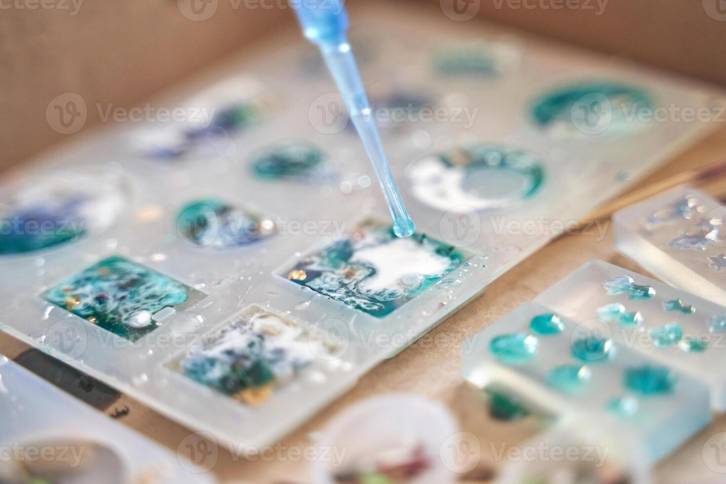 Close up of resin art process with colorful designs and pipette application on molded shapes. photo
