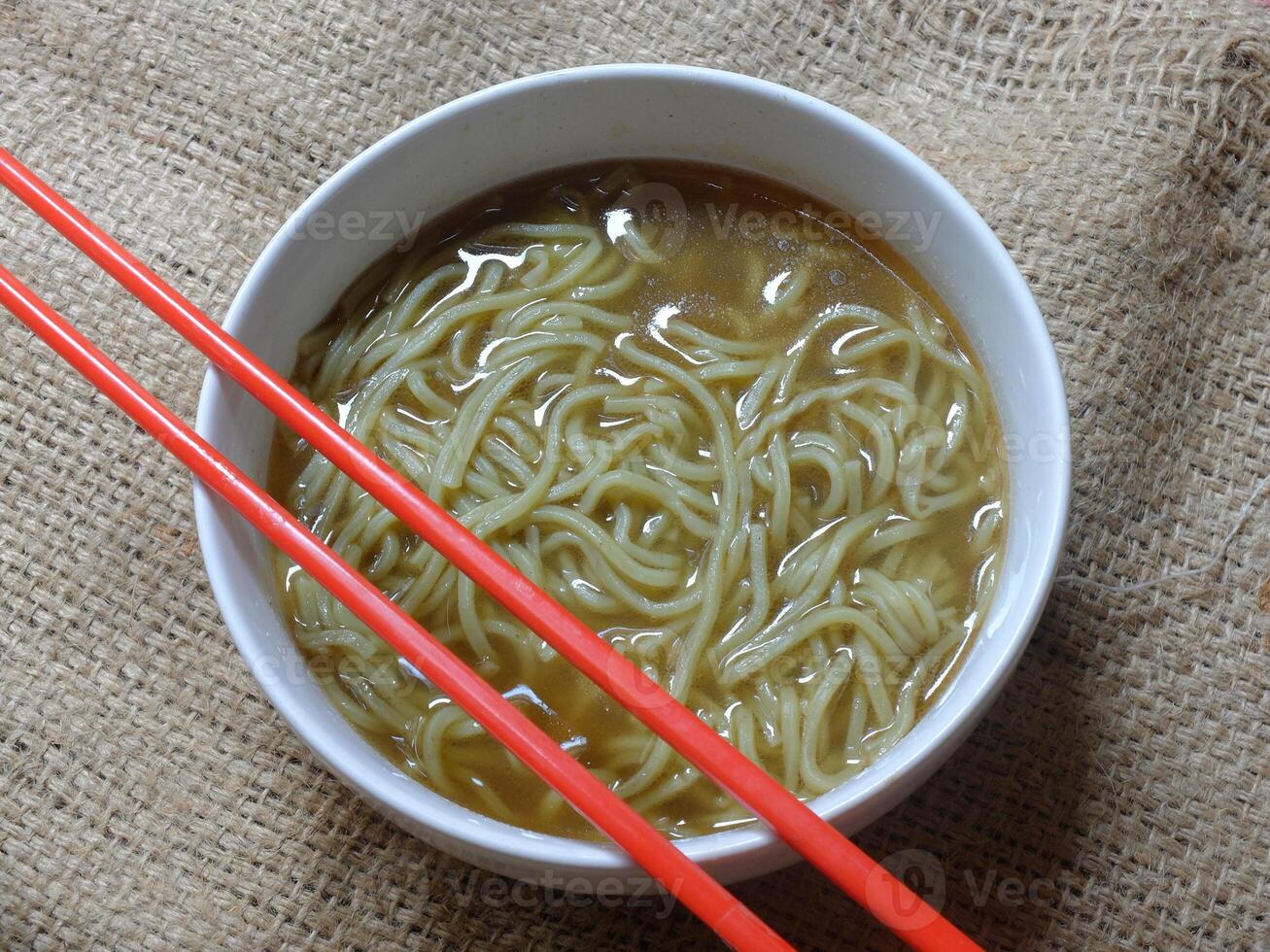 instant noodle soup in a white ceramic bowl. red chopsticks. photo