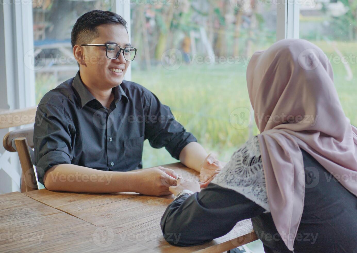Muslim husband and wife are relaxing at the camping site and appear to be smiling happily and looking at each other photo