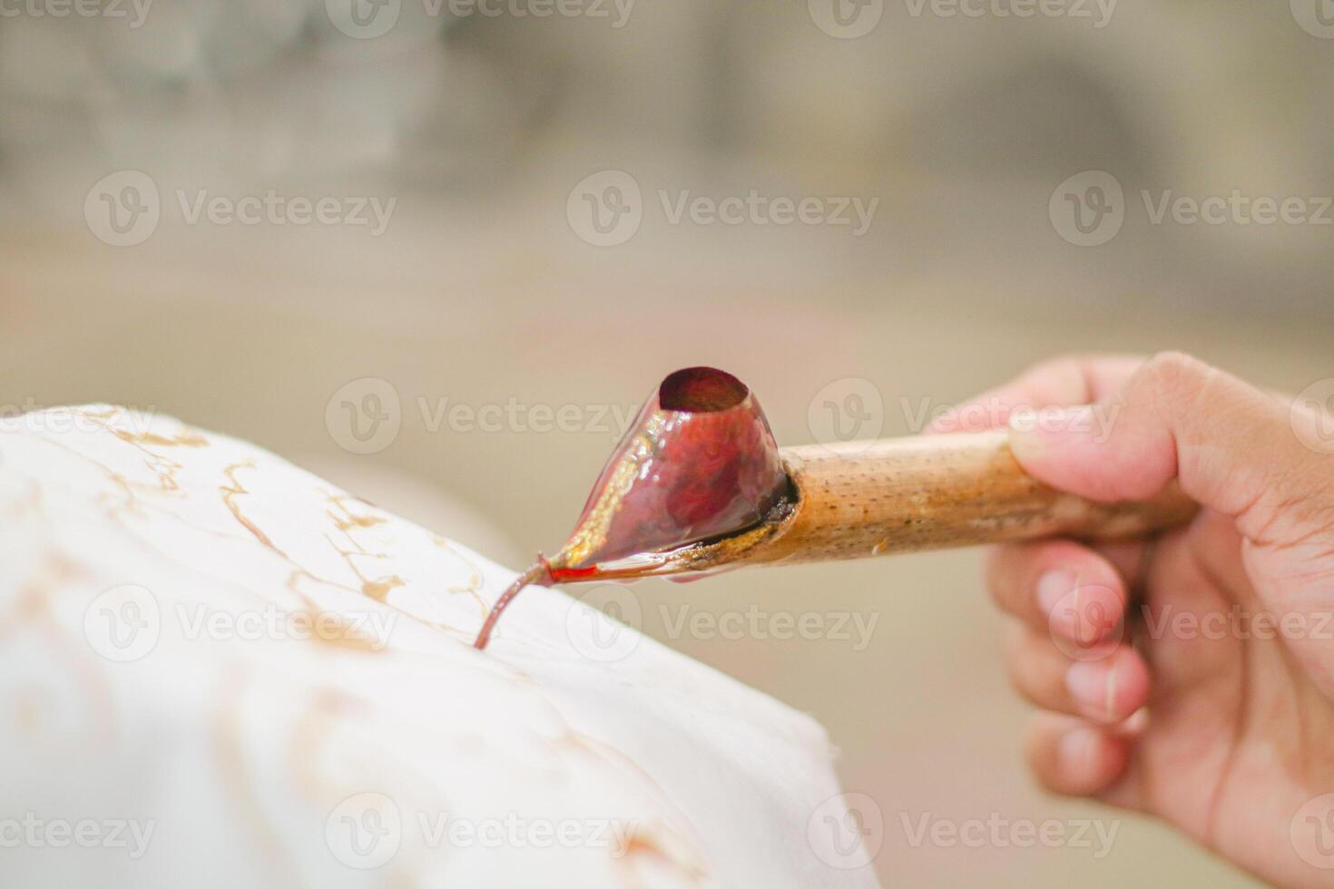 A woman delicately holds a canting tool, painting intricate batik designs on fabric in Indonesia, showcasing the nation's rich cultural heritage and traditional art photo