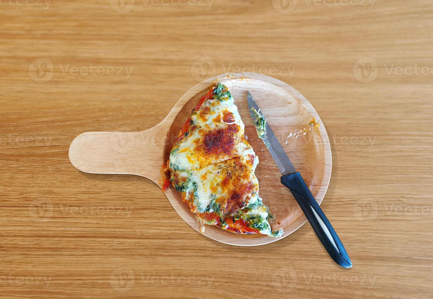 Spinach and cheese pizza, cut in half, Italian food, on a wooden table. photo