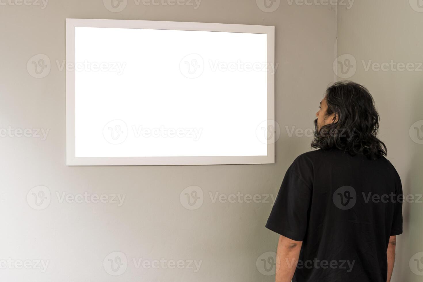 Person in an exhibition room, man standing in front of a blank canvas, a modern mockup design for advertising. lipping path. photo