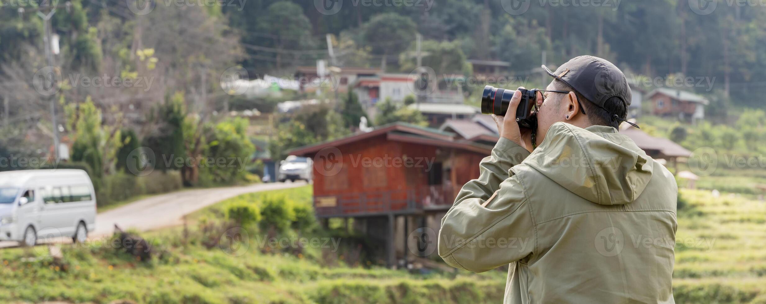 Young cheerful man photographer taking photographs with digital camera in a mountains, Travel and active lifestyle concept. photo