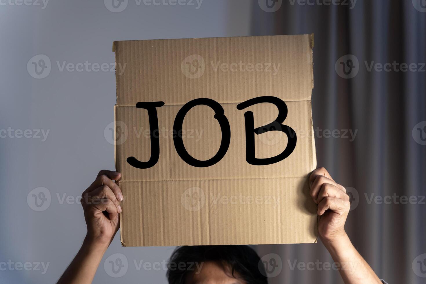 Business man holds up a cardboard sign with the words job. A man holding a cardboard with an inscription needs a job. Concept of job search, a reduction. photo