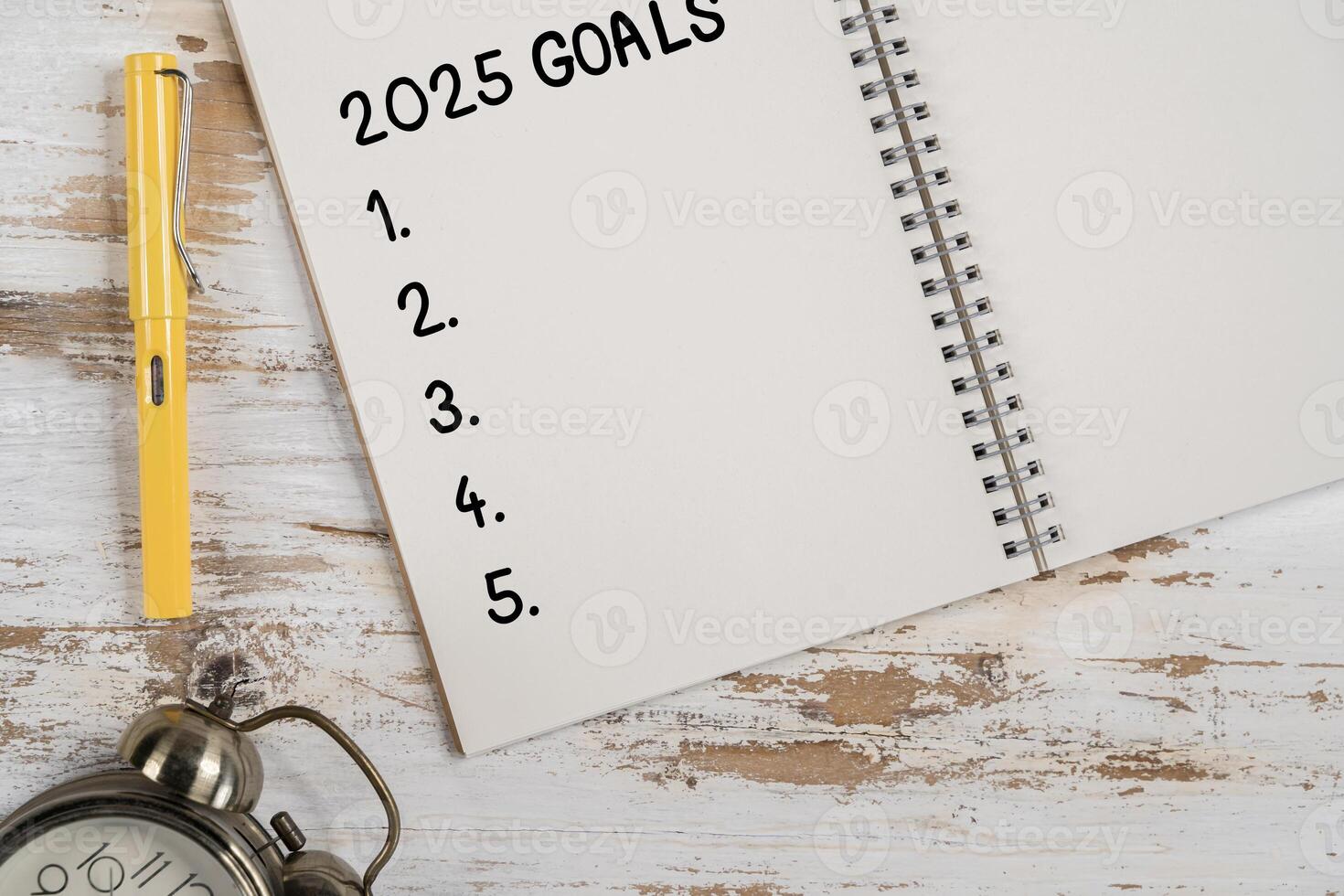 A 2025 goal-setting setup with a notebook, black coffee cup, and pen arranged on a wooden table, top view with copy space. photo