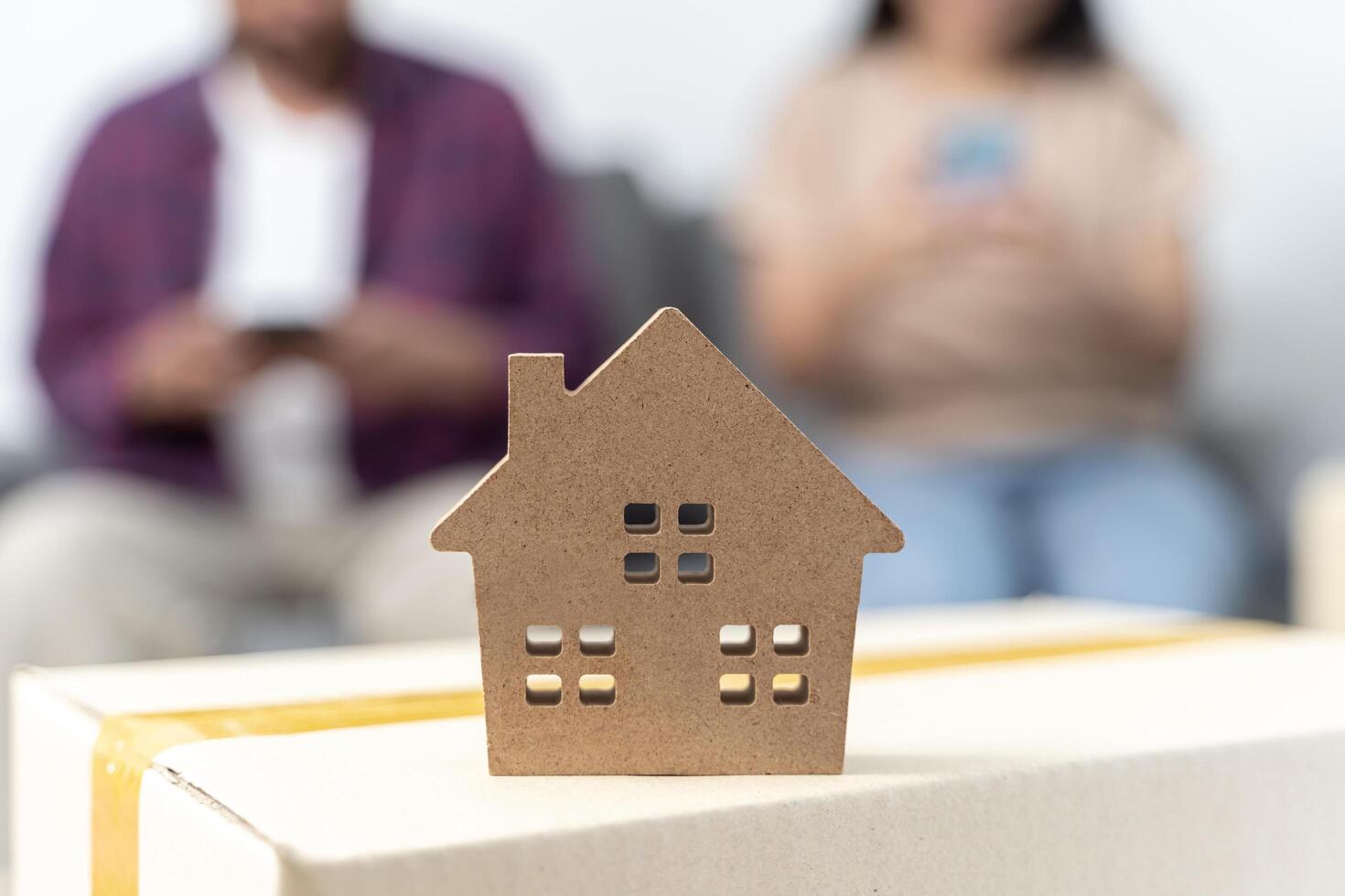 A young couple uses a smartphone to find information about moving house. Male and female and house model. photo