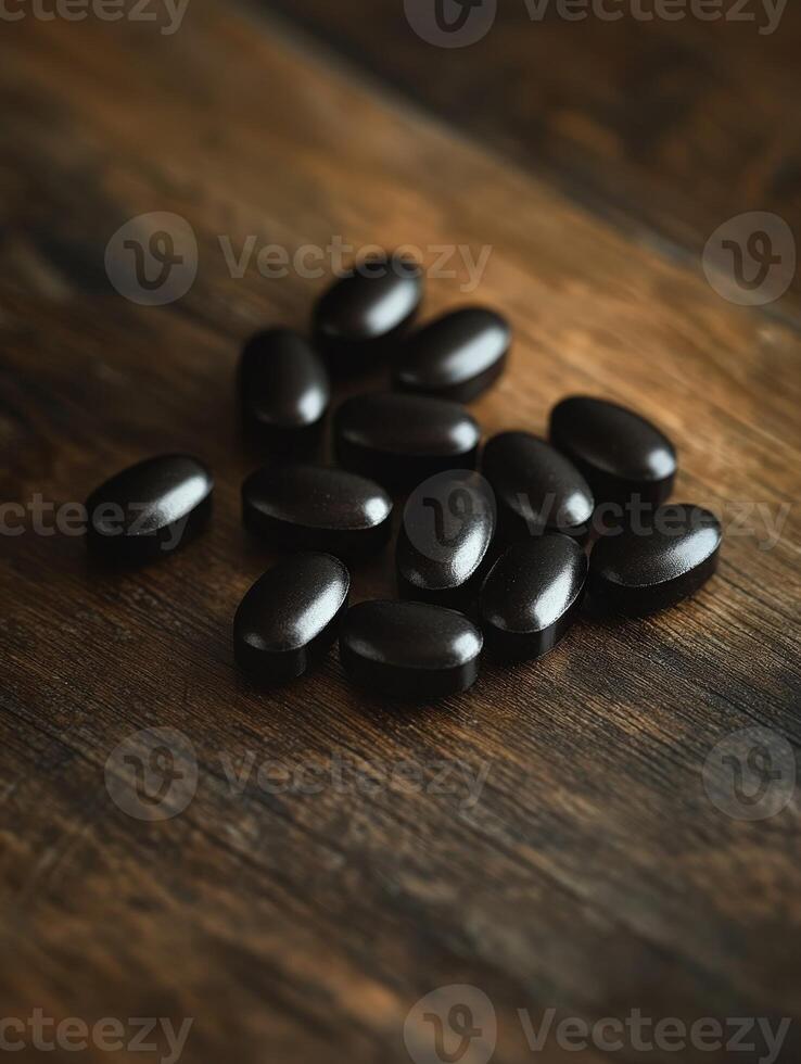 Dark capsules scattered on a wooden surface create a striking visual contrast photo