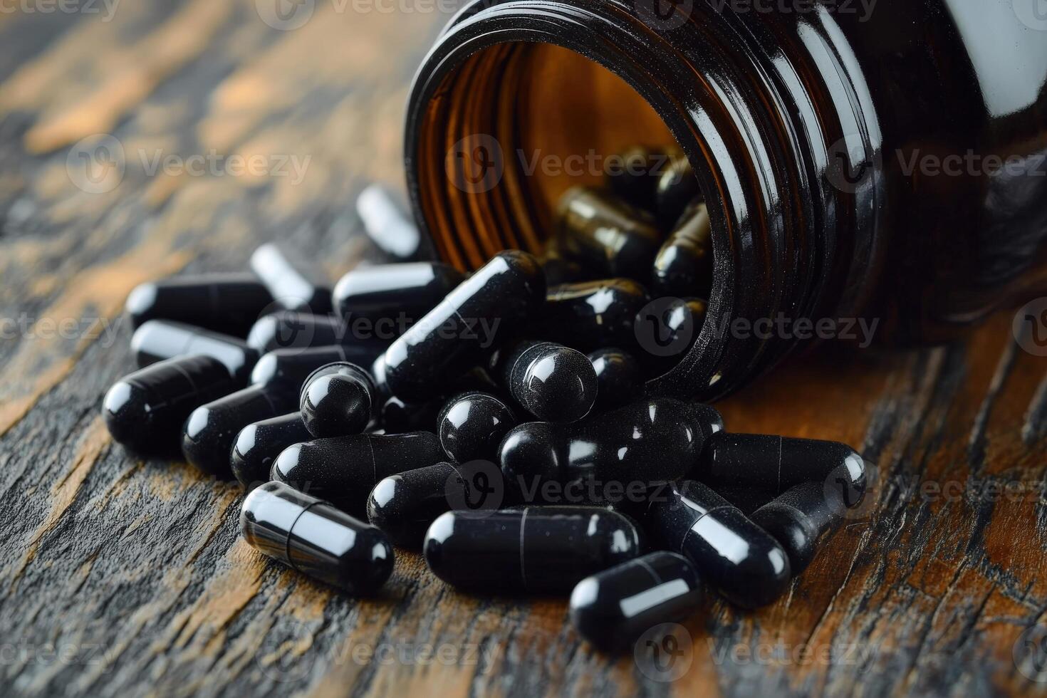 Black capsules spill from a brown bottle on a wooden surface photo