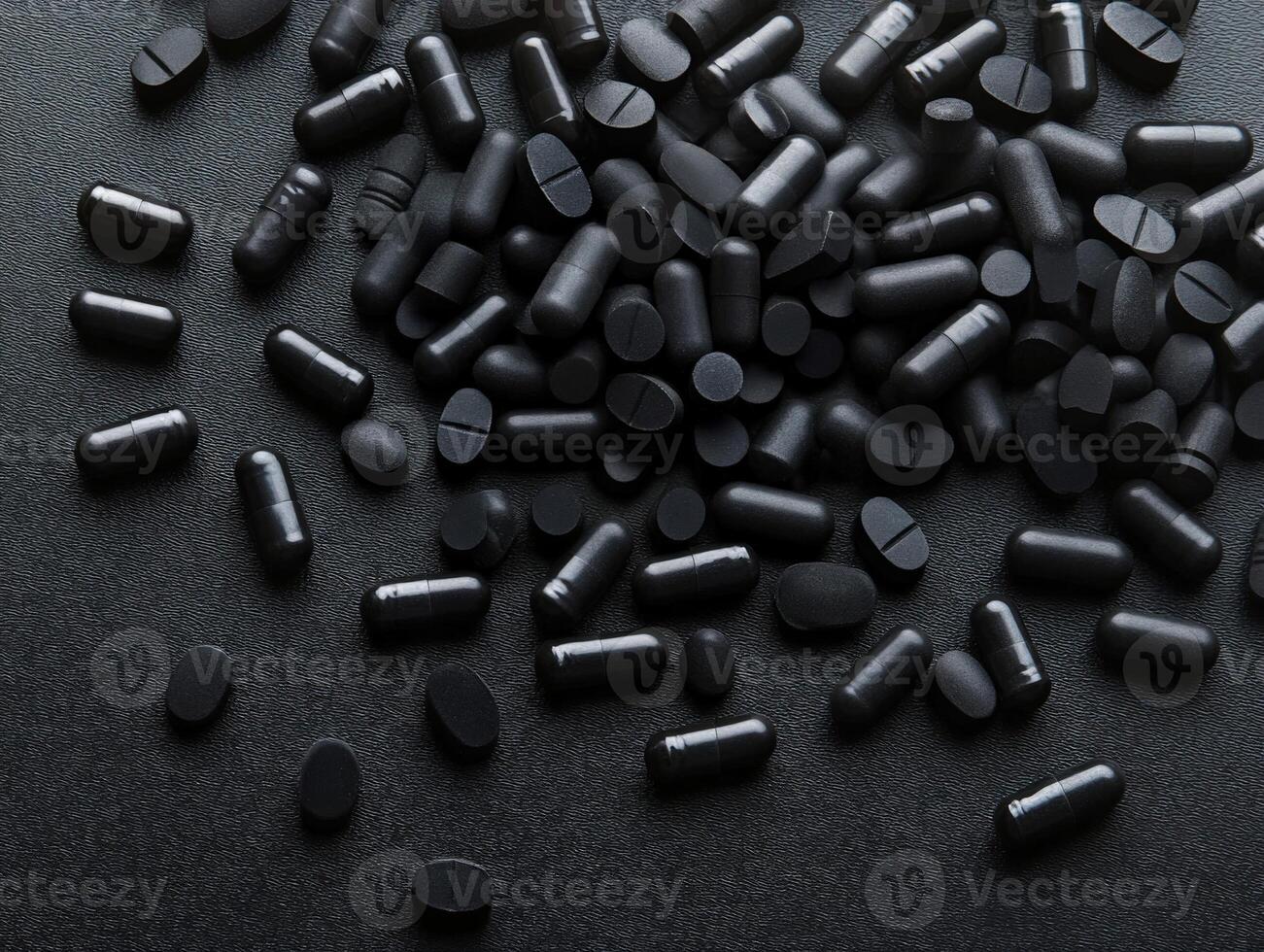Variety of black dietary supplements scattered on a dark surface photo