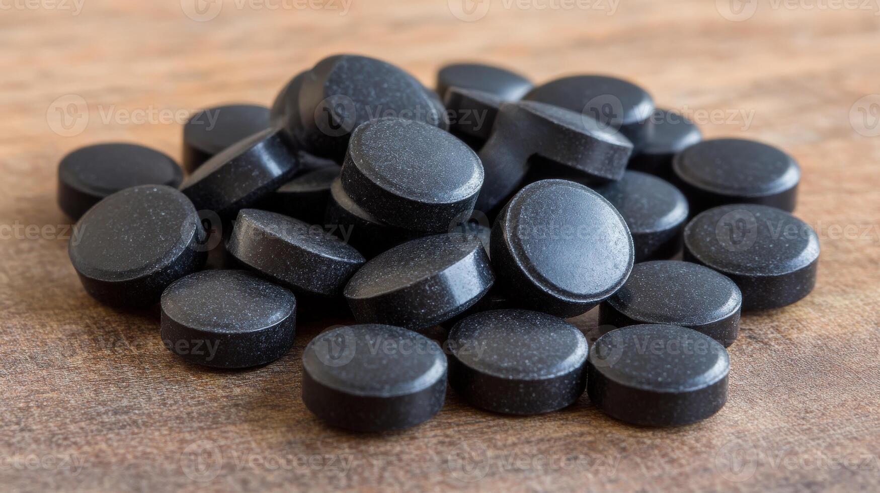 Black circular tablets arranged on a wooden surface in a natural setting photo