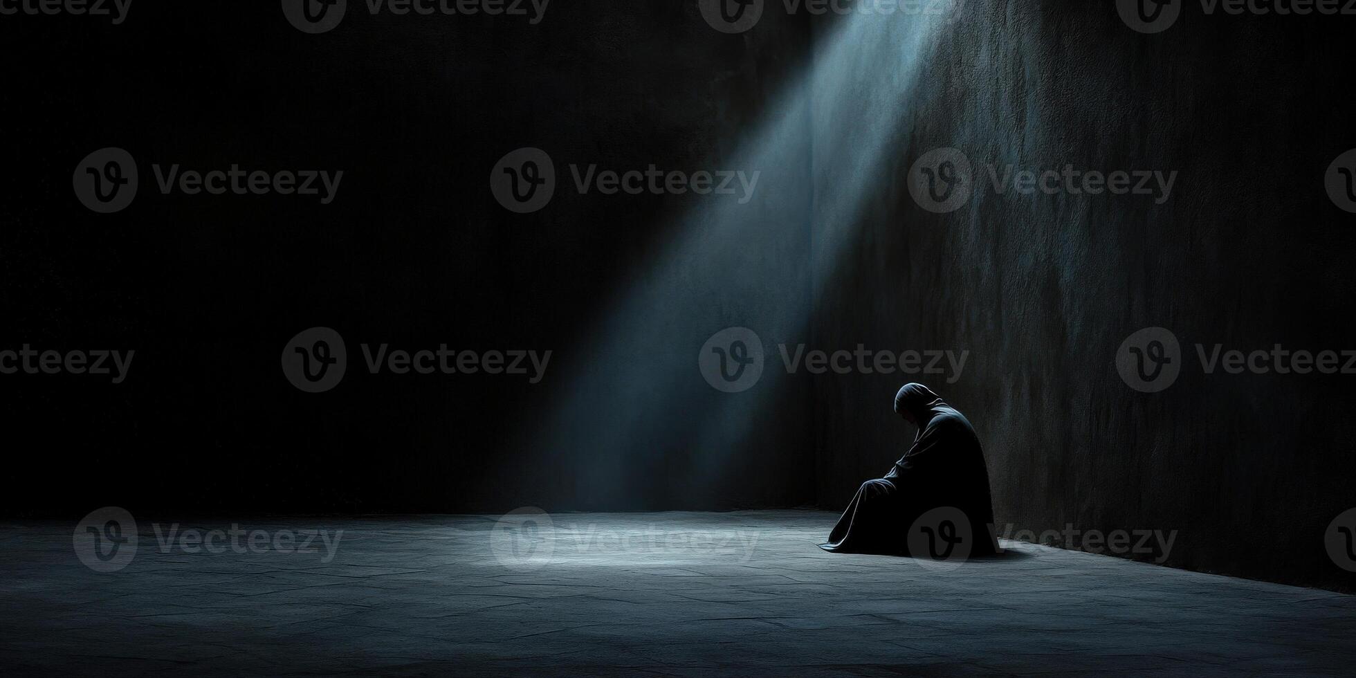 Solitary figure in dark space illuminated by a single beam of light photo