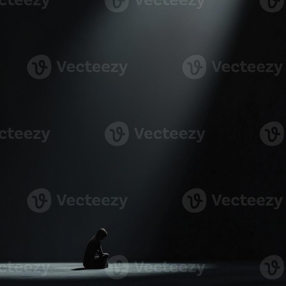 Solitary figure in a dark space illuminated by a focused light beam photo