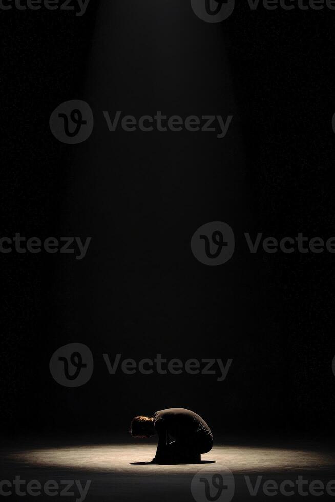 Dramatic performance under a spotlight with person in a vulnerable pose photo