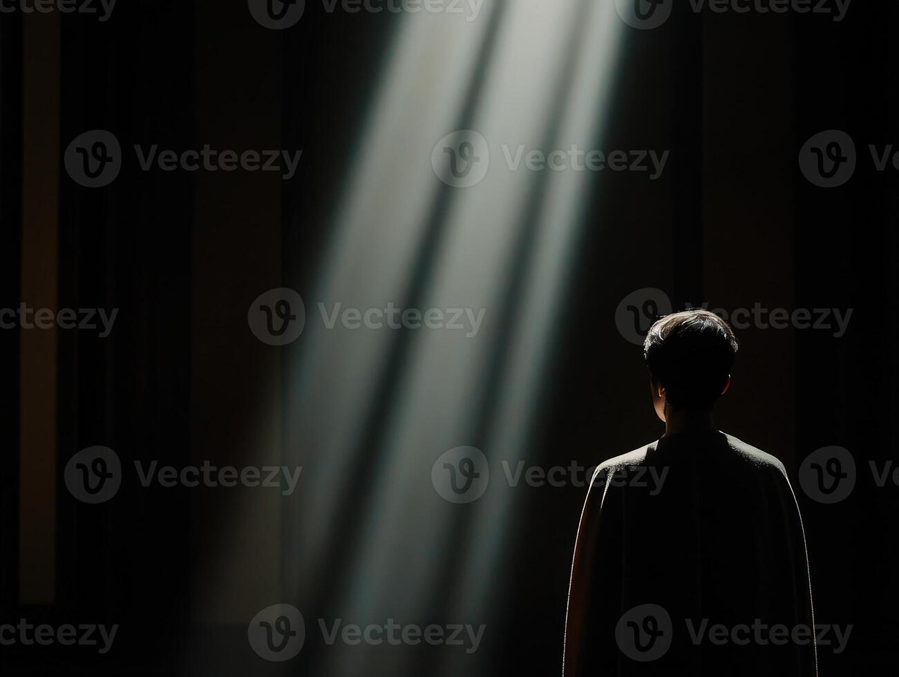 Light illuminates figure in dark space, creating a contemplative atmosphere photo