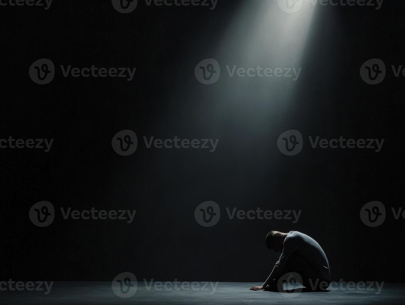 A man sits in a dimly lit area, bent over with a posture of reflection photo