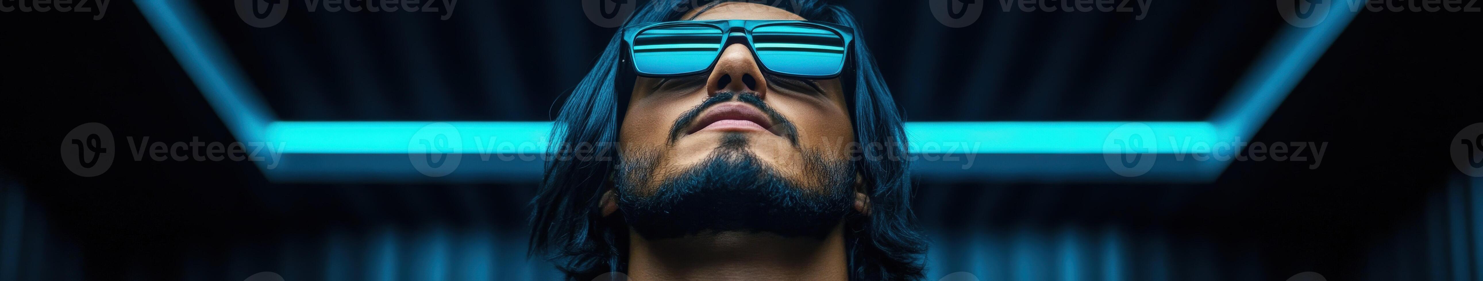Stylish man wearing sunglasses gazes upward under neon lights photo