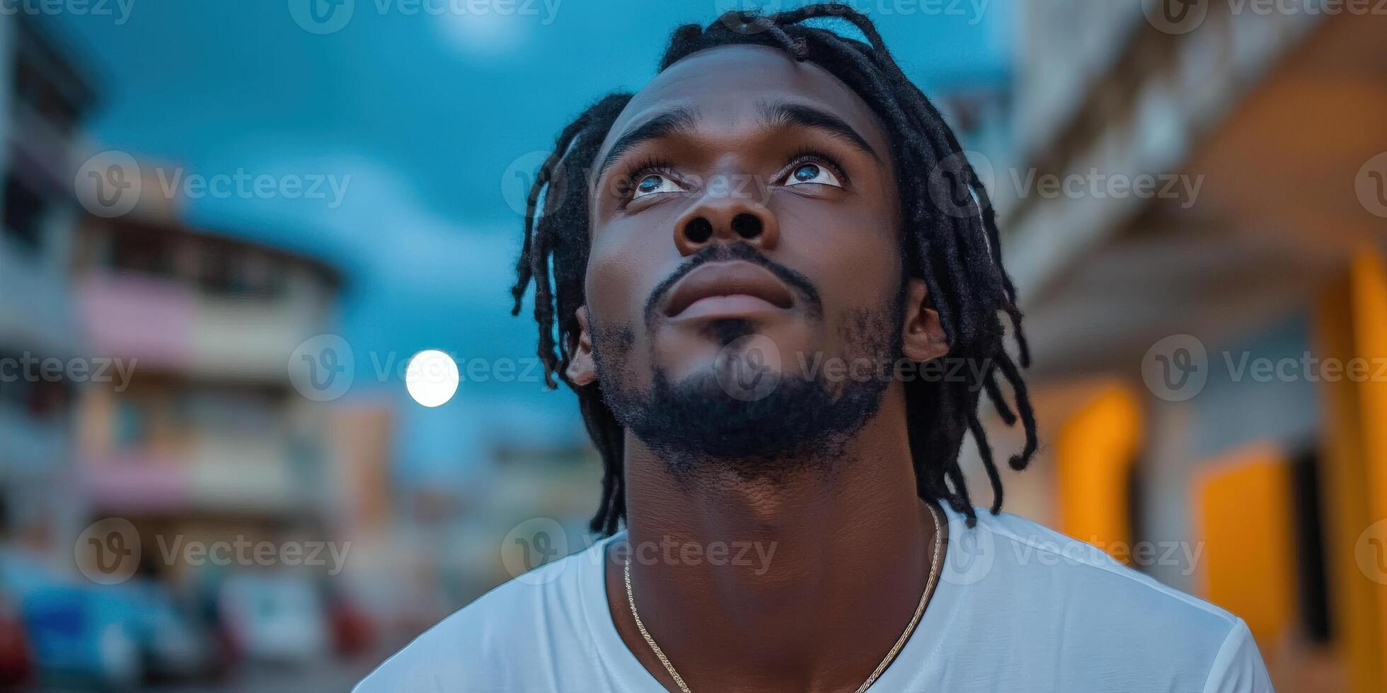 Man gazing upwards with hope in an urban setting during twilight photo