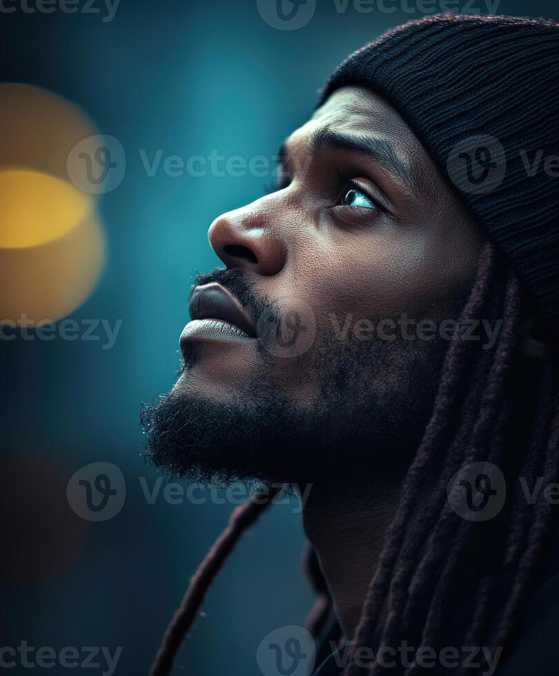 Man with dreadlocks gazing upward in an urban evening setting photo