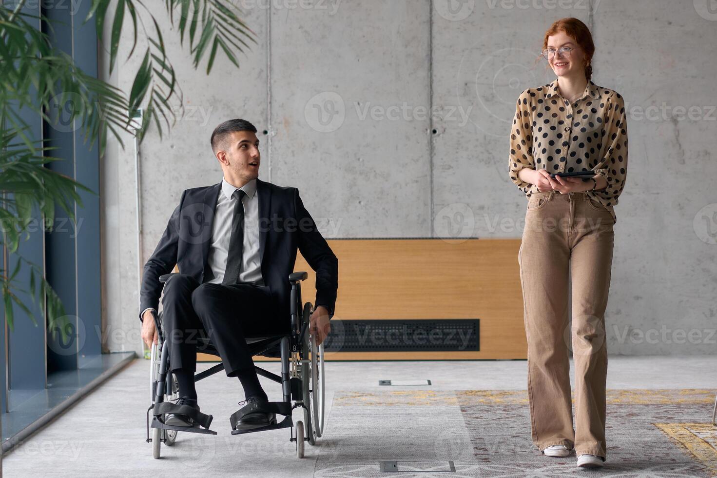 Director in a Wheelchair Engaging in a Business Discussion with a Colleague While Navigating a Modern Office photo