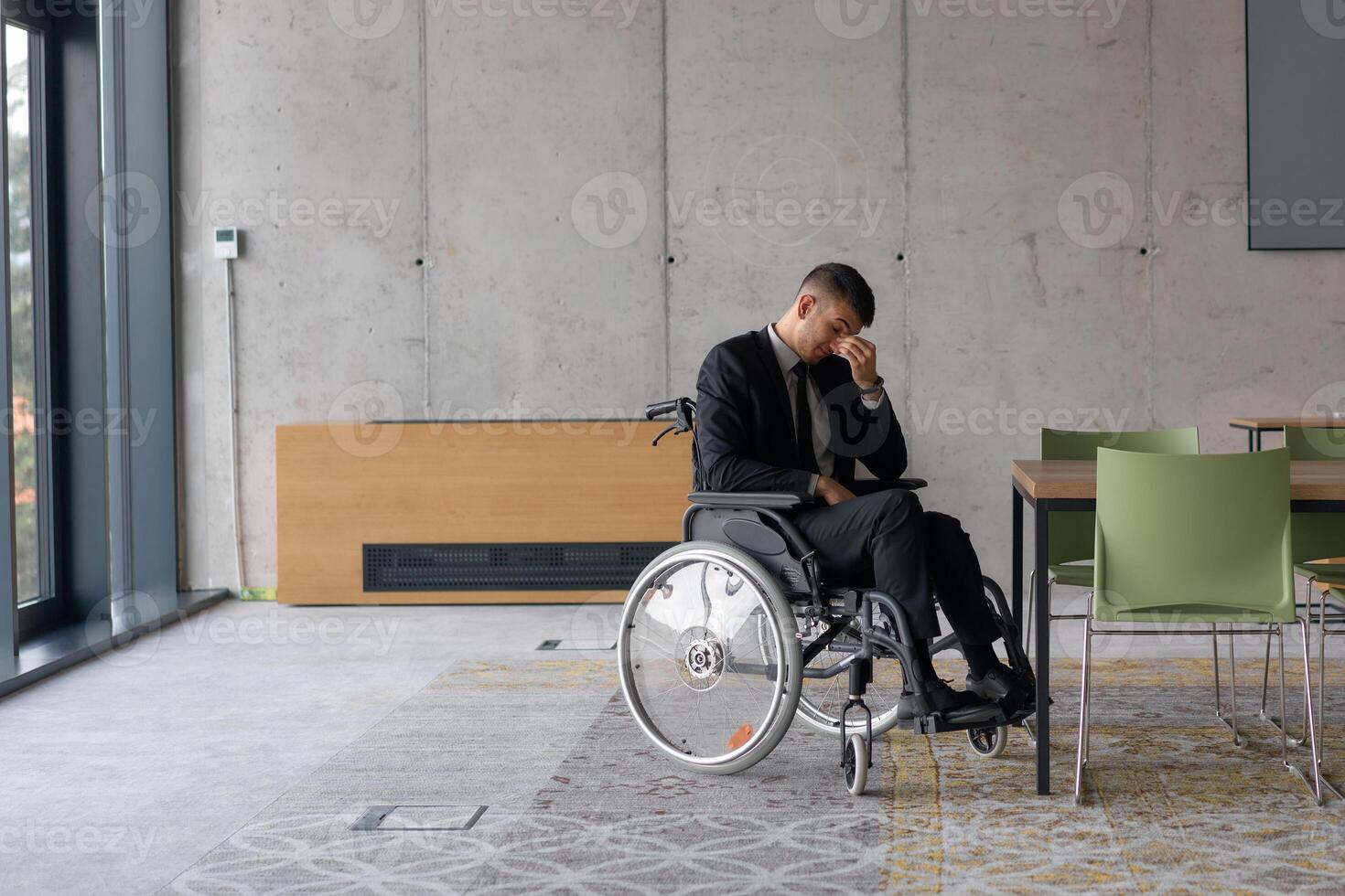 A director in a wheelchair sitting alone in an empty office, deeply reflecting on business strategies and decisions, contemplating the path forward with focused determination. photo