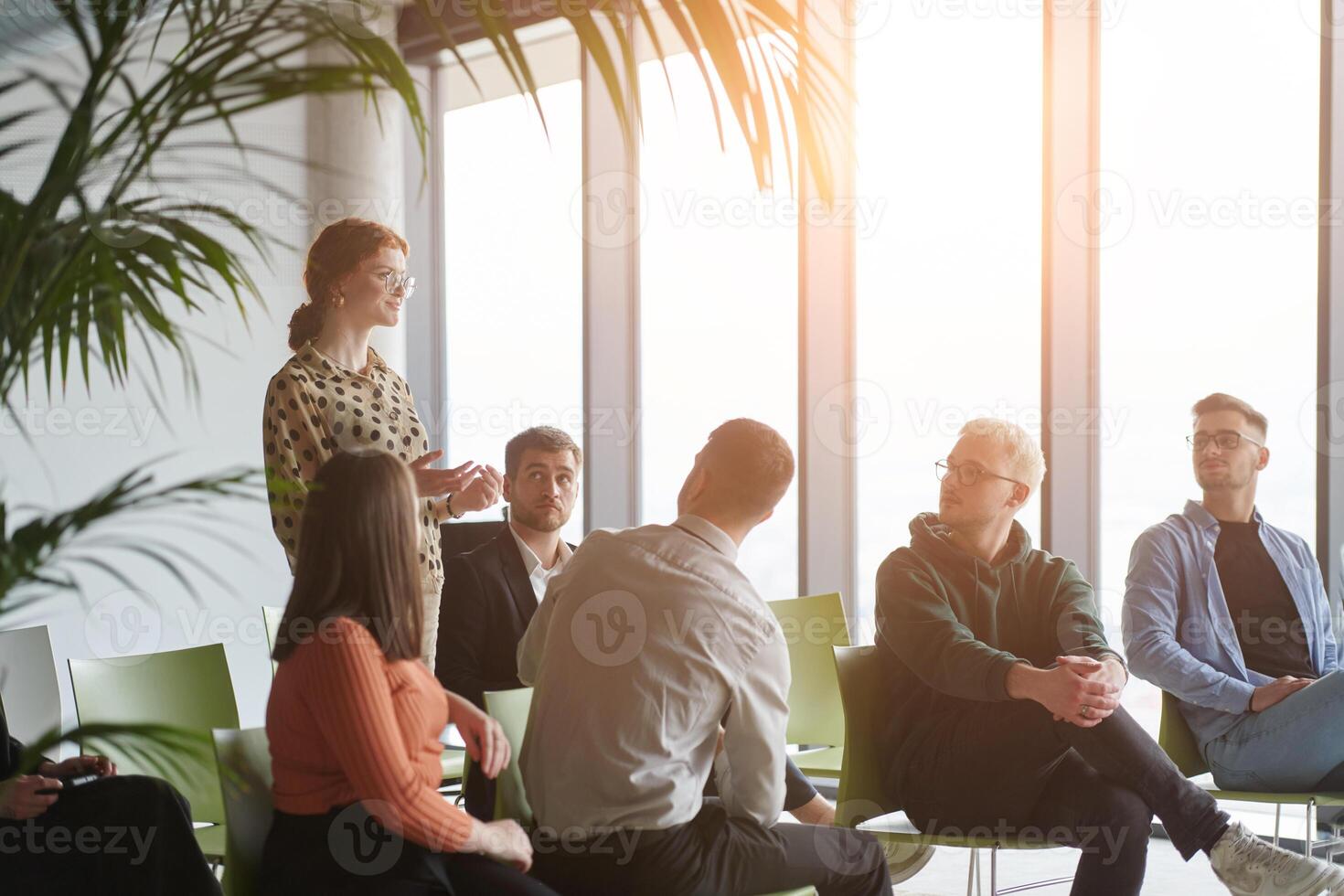 A diverse group of business professionals sits attentively in a modern office, actively participating in a training session led by an instructor, focusing on the latest technological advancements in photo