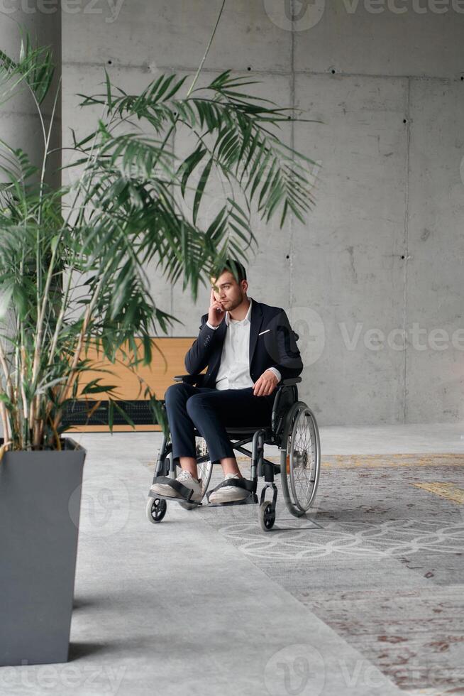 A director in a wheelchair sitting alone in an empty office, deeply reflecting on business strategies and decisions, contemplating the path forward with focused determination. photo