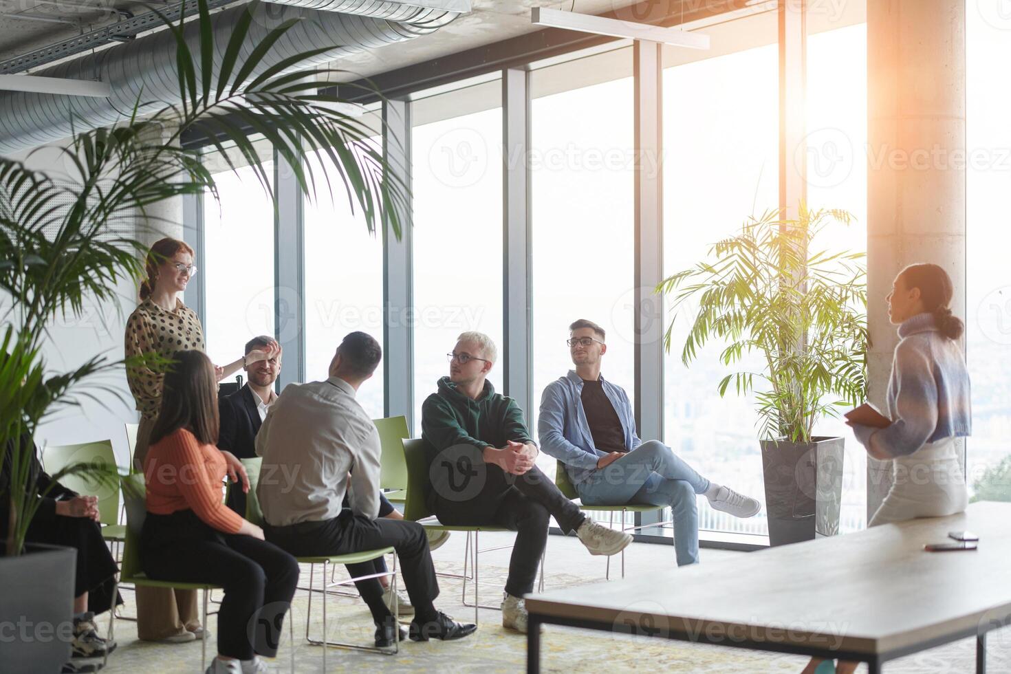 A diverse group of business professionals sits attentively in a modern office, actively participating in a training session led by an instructor, focusing on the latest technological advancements in photo