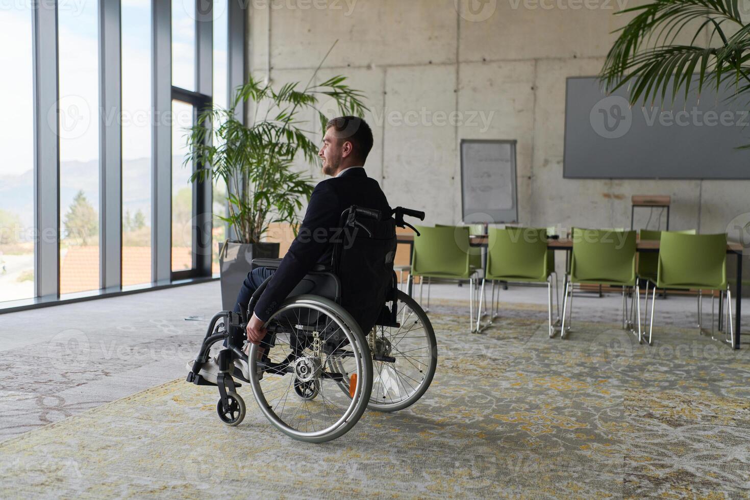 A director in a wheelchair sitting alone in an empty office, deeply reflecting on business strategies and decisions, contemplating the path forward with focused determination. photo