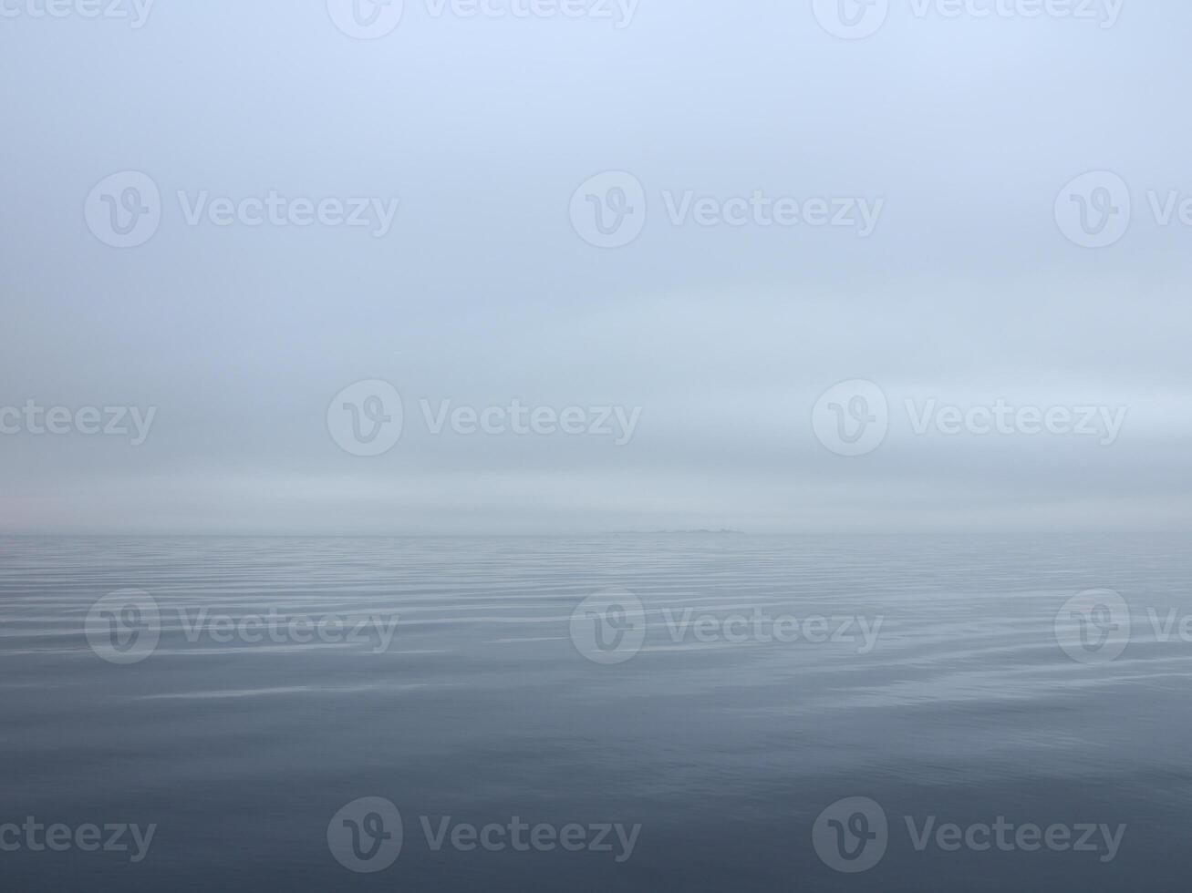 thick white fog fell on the sea, calm and silence, the water merges with the sky photo