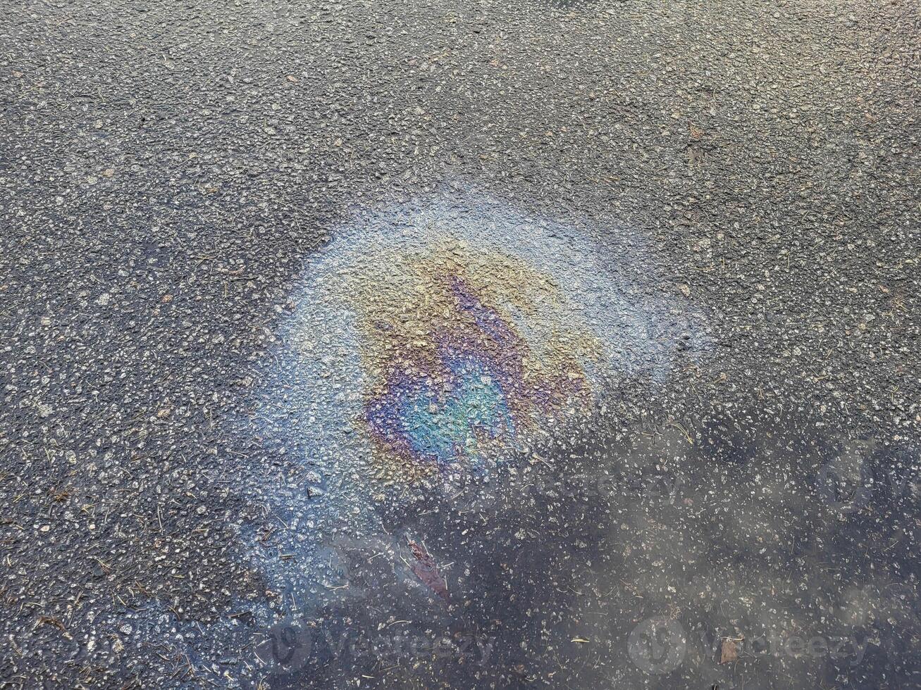 A rainbow spot of gasoline on the asphalt is a donkey of rain on a summer day. photo