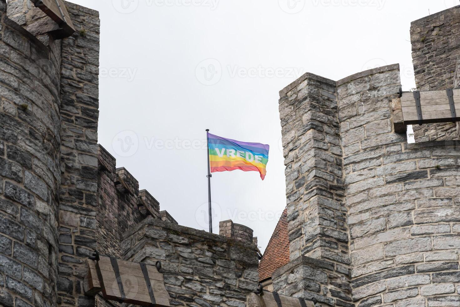 rainbow flag on the roof of the Gravensteen in Ghent, Belgium, with the Dutch inscription vrede - peace, a symbol of gays, lesbians, bisexuals and transgender people, the LGBT social movements, photo