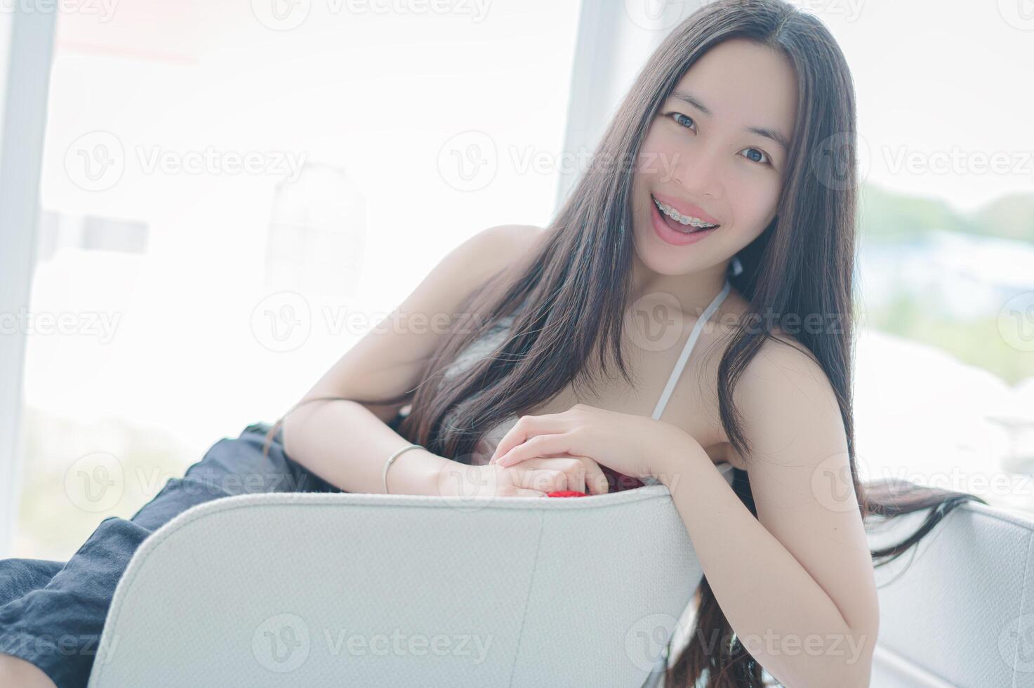 A woman sitting on a white chair smiling photo