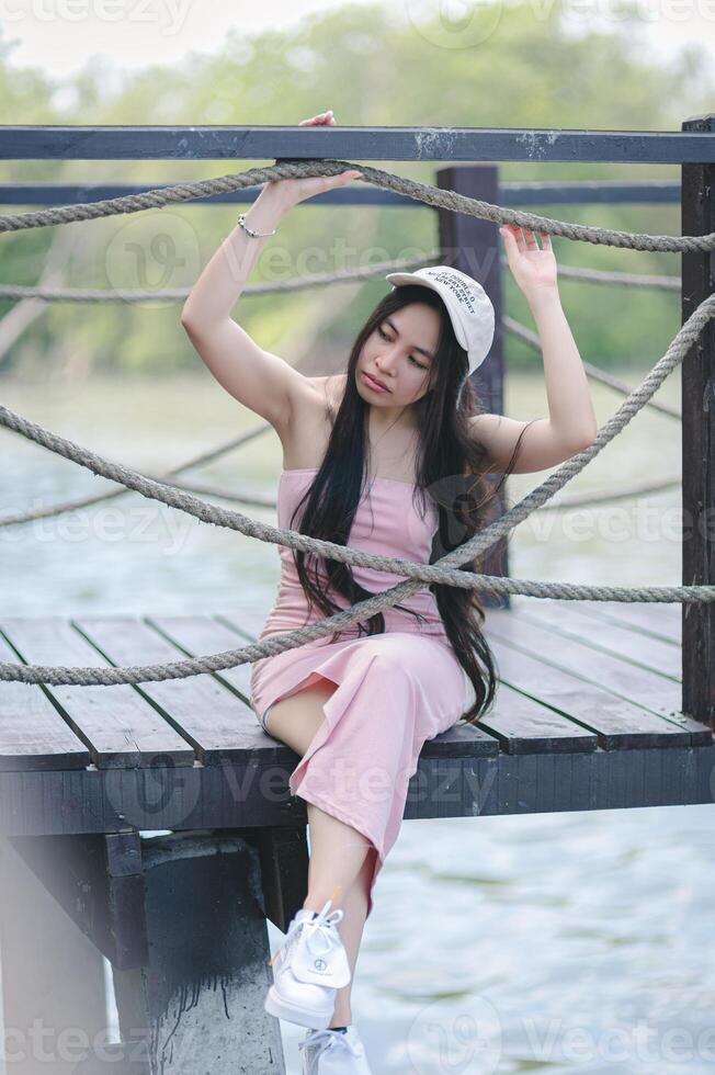 A woman sitting on a dock with her arms up photo