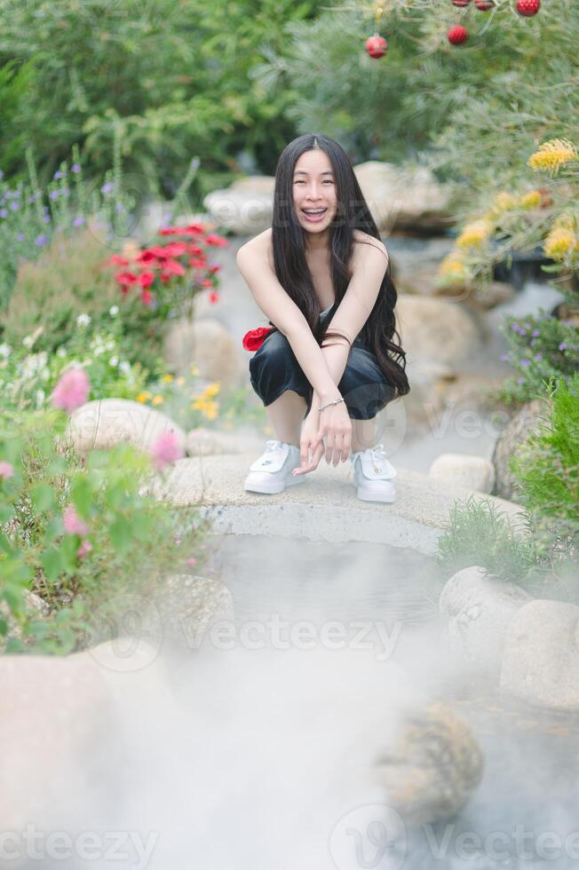A woman crouches down on a stone bridge photo