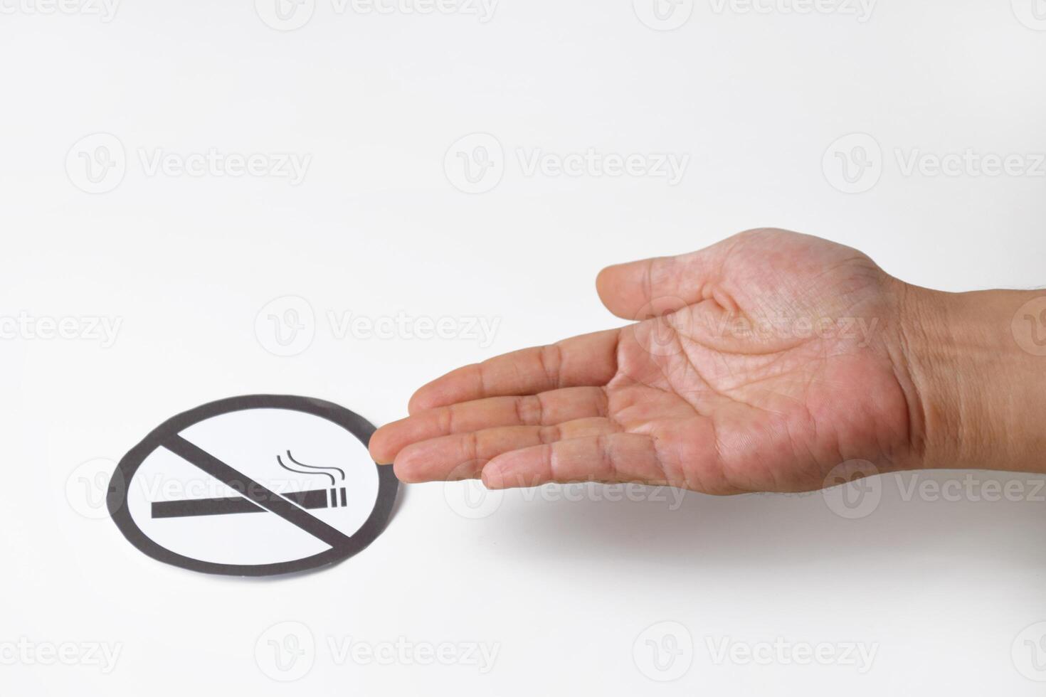 Man's hand holding a no smoking symbol made of round paper photo