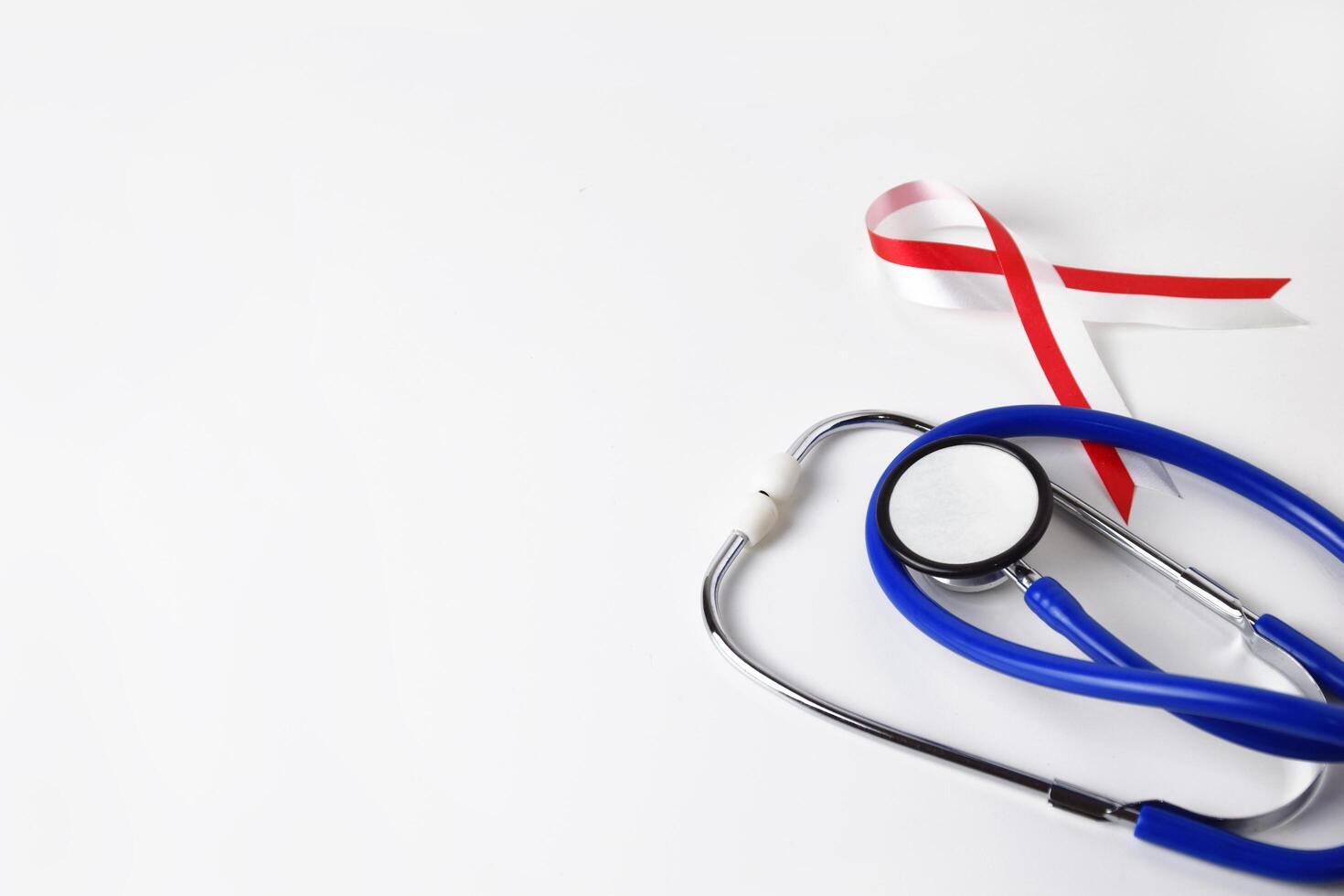 Red and white ribbon and doctors stethoscope close up photo