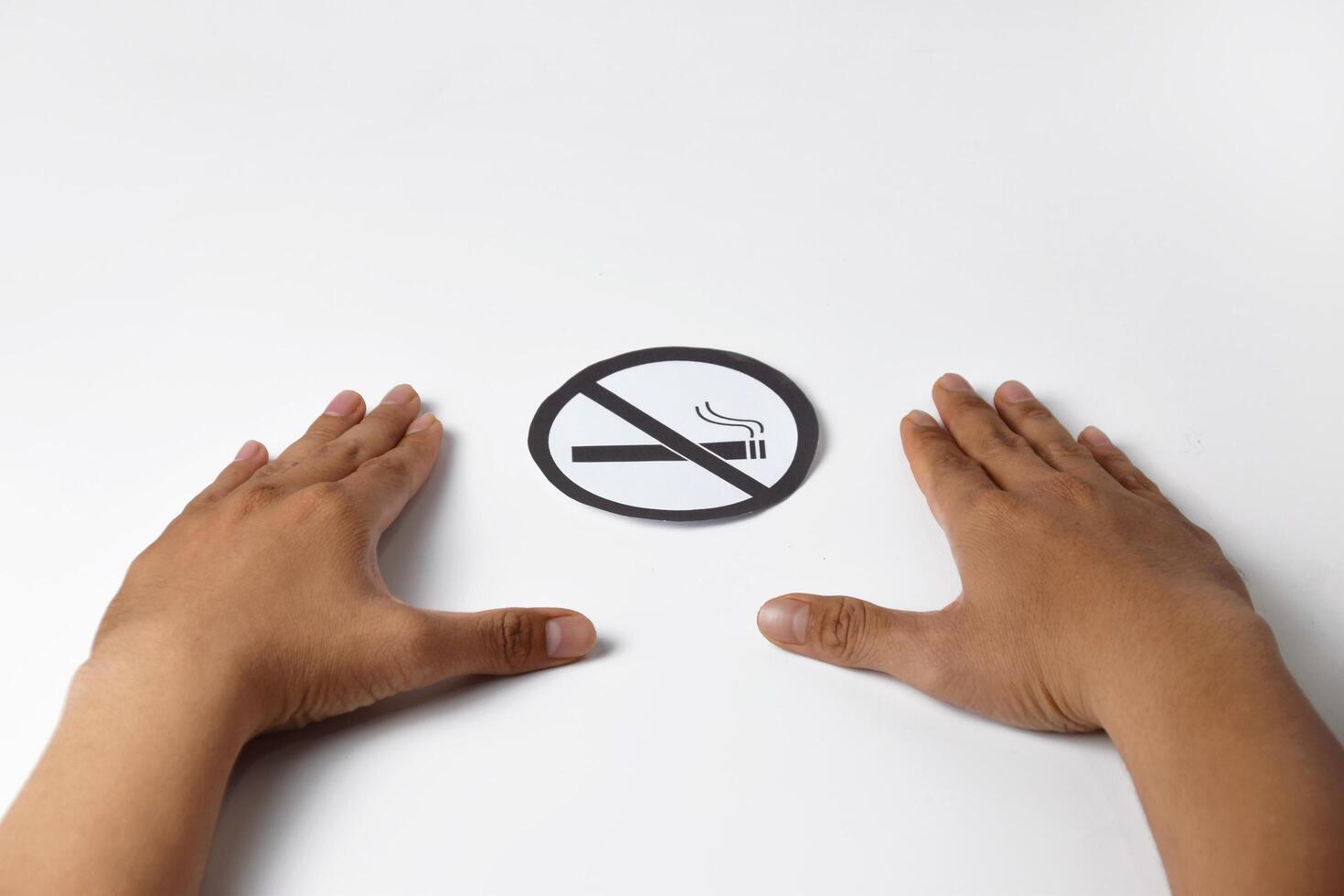 A person's hands show a no smoking sign using paper on a white background photo