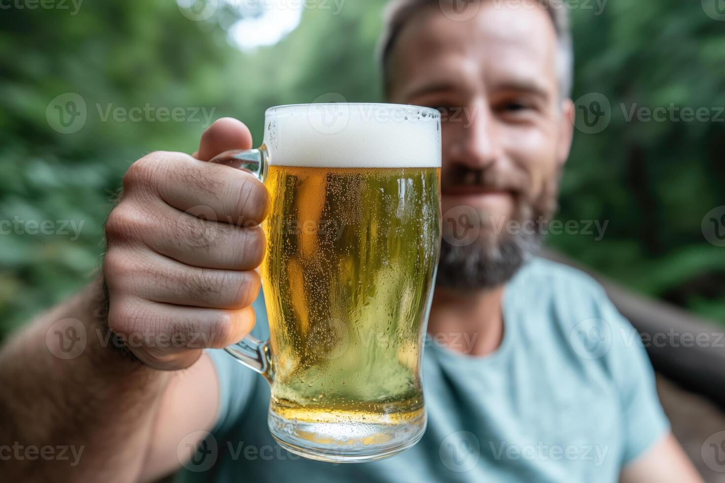 Man holding a mug of beer in the forest. Close-up. photo