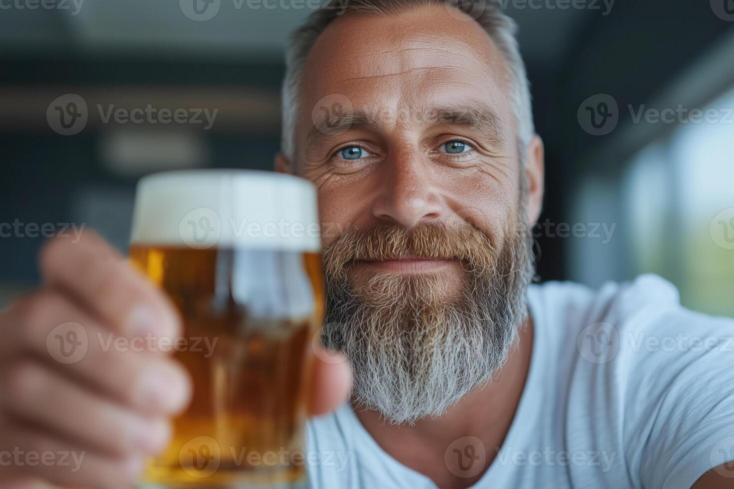 Close up portrait of handsome bearded man drinking beer. He is looking at camera and smiling photo