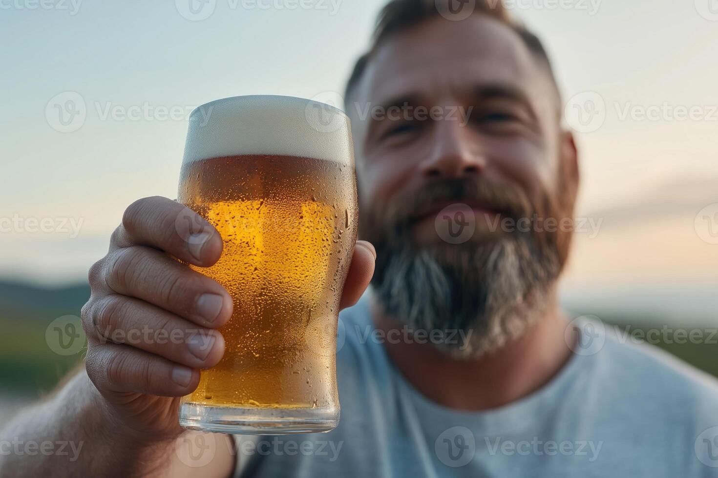 Close-up of a bearded man holding a glass of beer outdoor photo