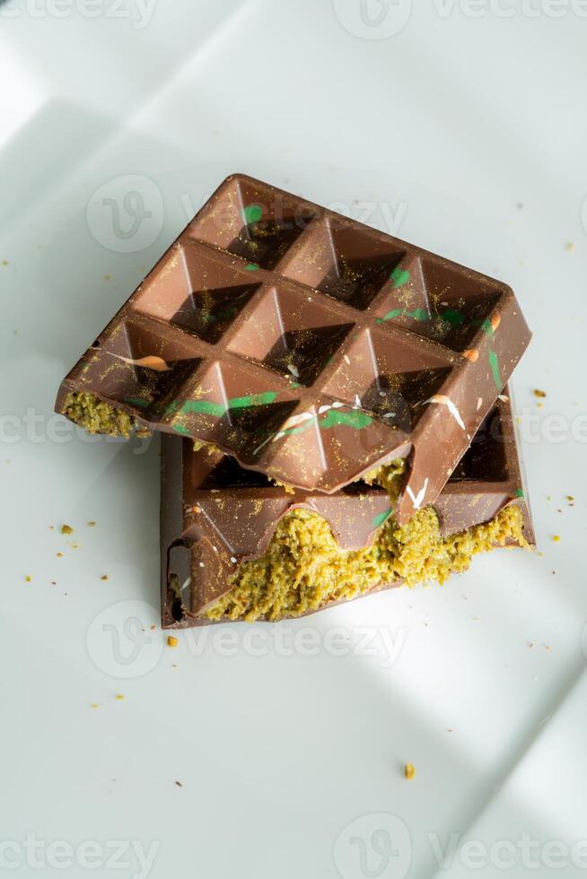 Top view of Dubai chocolate bar with pistachio paste, tahini and kataifi filling on white plate. Confectionery and sweets. photo