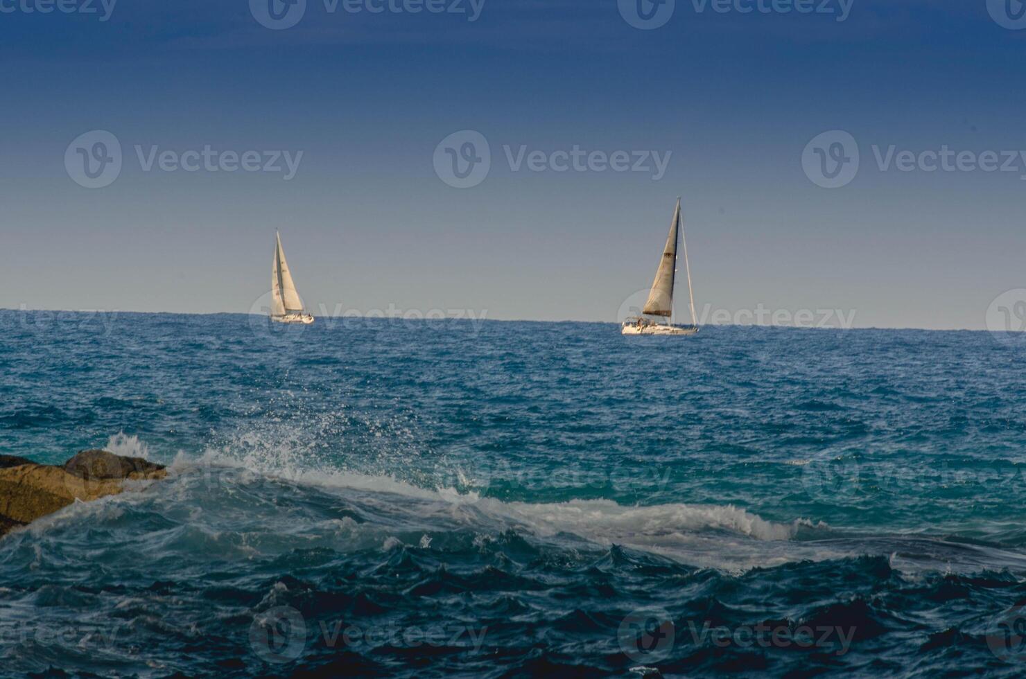 Serene Ocean View with two Sailboats and Crashing Waves background photo