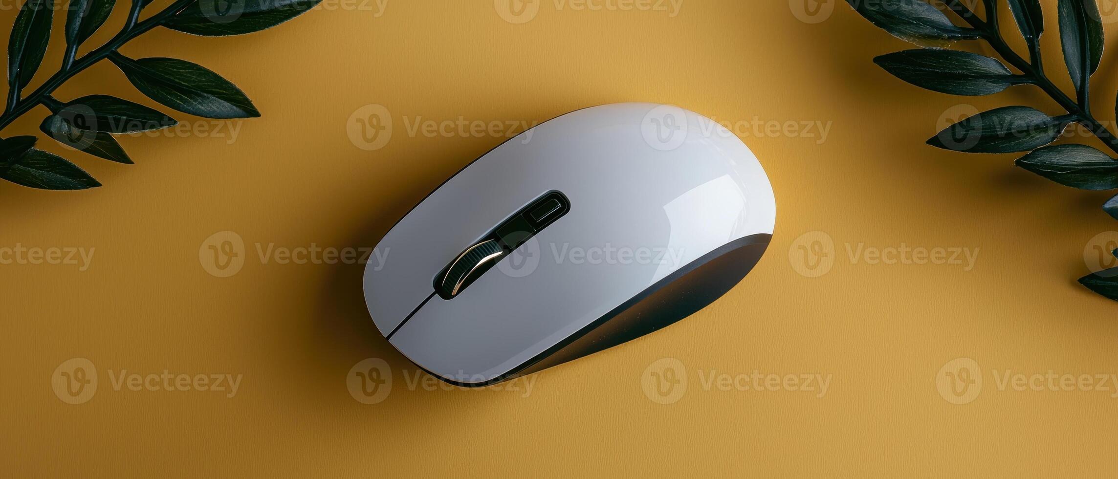 White wireless computer mouse on yellow background with dark green leaves photo