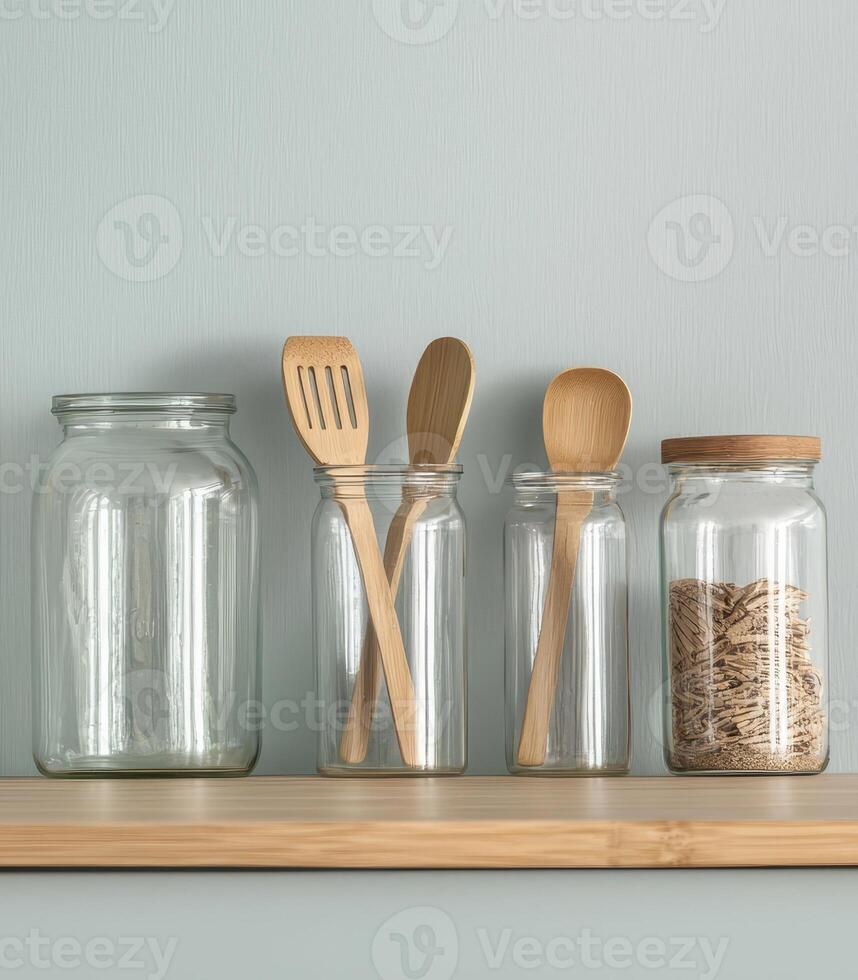 Plastic free campaign. Clear jars and wooden utensils arranged on a wooden shelf against a light wall. photo